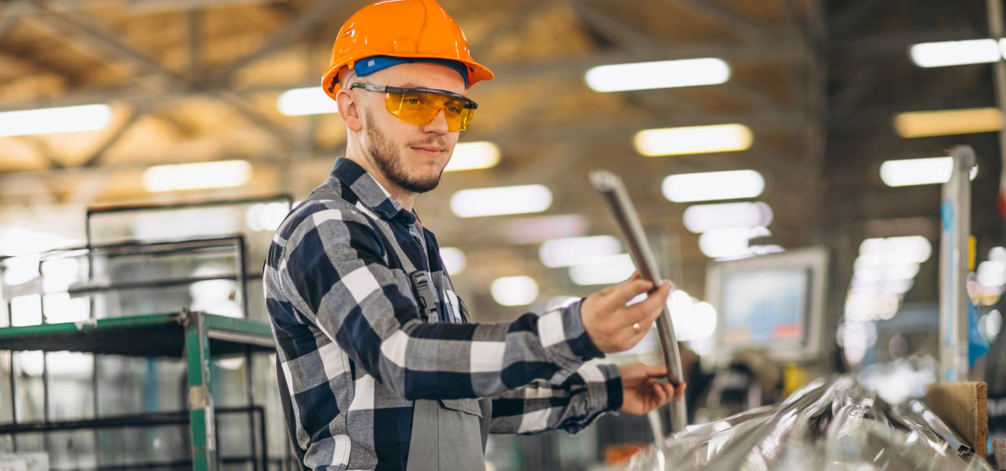 Opérateur inspectant une pièce métallique dans un atelier de fabrication