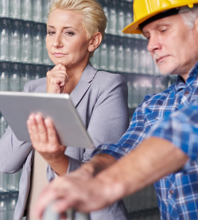 Deux personnes consultant une tablette à proximité d’une installation industrielle.
