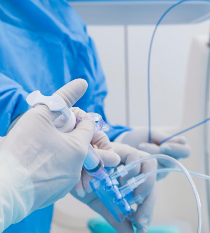 Professionnel de santé manipulant un dispositif médical composé de tubulures et de raccords.