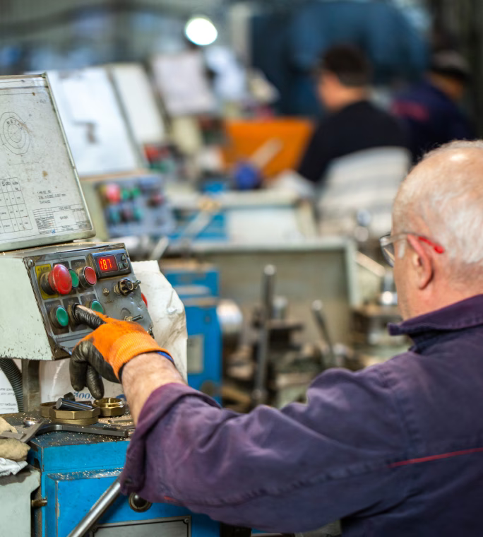 Opérateur réglant une machine de production dans un atelier industriel.