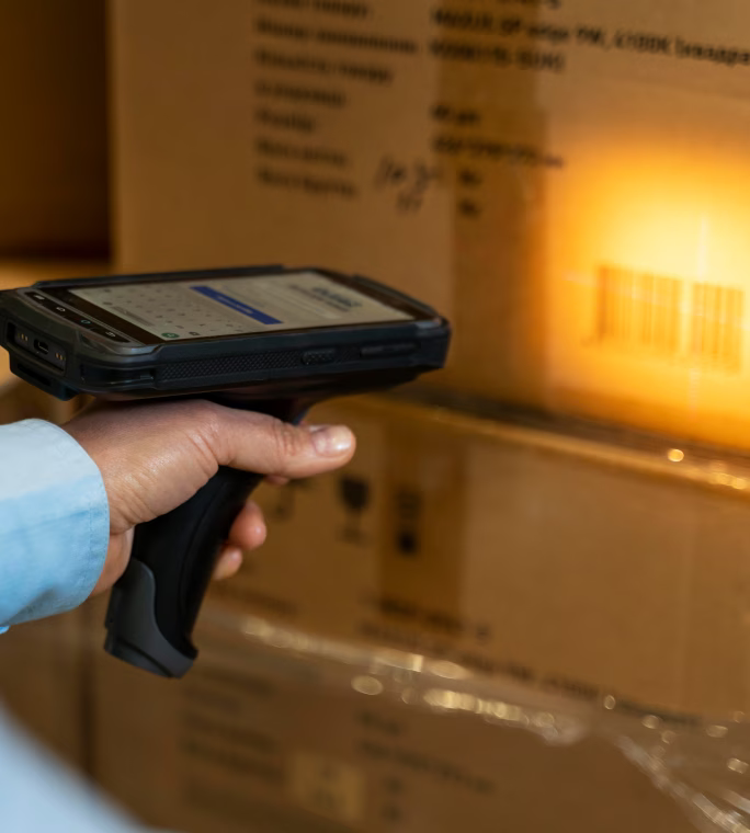 Opérateur scannant le code-barres d’un carton dans une zone de stockage