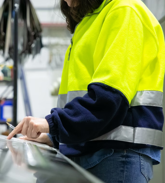 Personne en tenue haute visibilité utilisant le pupitre de commande d’une machine industrielle.