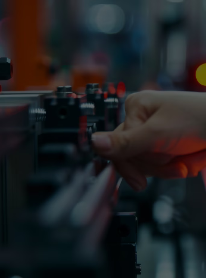 Gros plan sur une main ajustant un mécanisme sur une machine industrielle.
