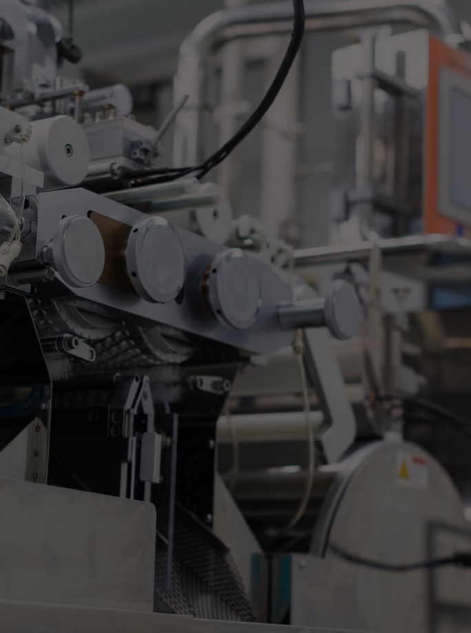Gros plan sur les mécanismes, les câbles et les carters métalliques d’une machine industrielle.