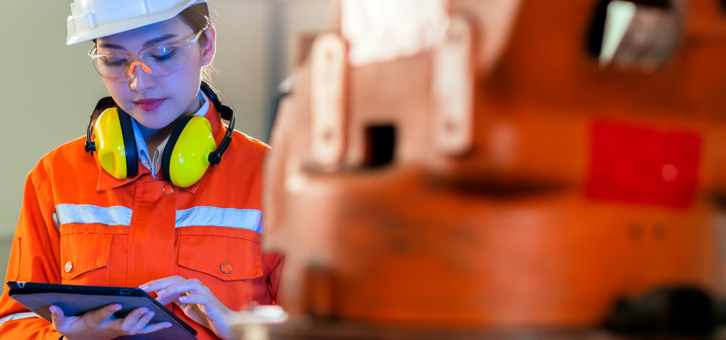 Opératrice utilisant une tablette à proximité d’un équipement de production industriel